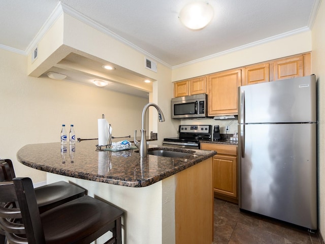 kitchen with visible vents, appliances with stainless steel finishes, ornamental molding, a sink, and a kitchen breakfast bar