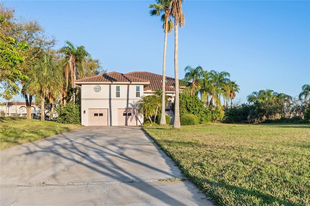 mediterranean / spanish-style house featuring a tile roof, driveway, a front lawn, and stucco siding