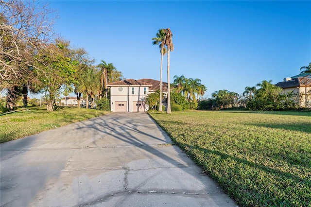 view of front facade with a front yard, concrete driveway, and an attached garage