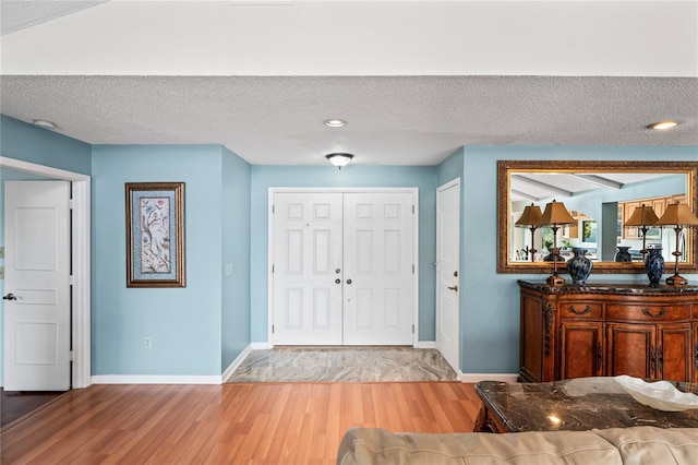 entrance foyer featuring a textured ceiling, baseboards, and wood finished floors