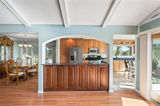 kitchen featuring appliances with stainless steel finishes, light wood-style flooring, a textured ceiling, and an inviting chandelier