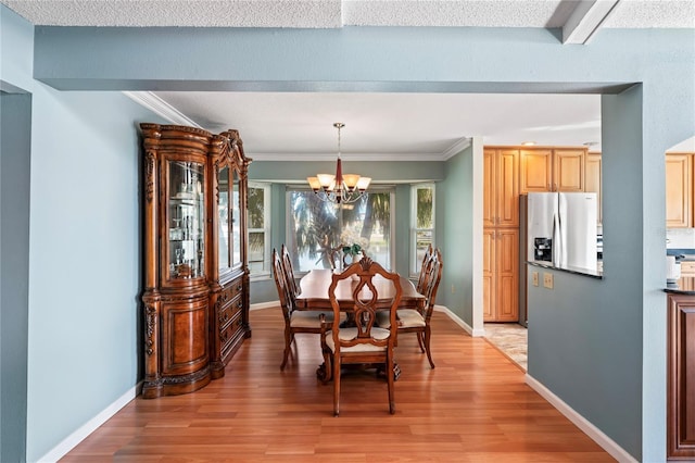 dining area featuring light wood-style floors, crown molding, baseboards, and an inviting chandelier