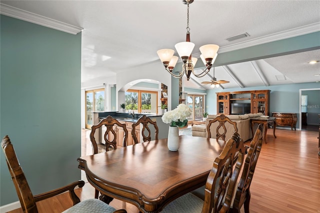 dining space featuring ceiling fan with notable chandelier, visible vents, vaulted ceiling, light wood finished floors, and crown molding