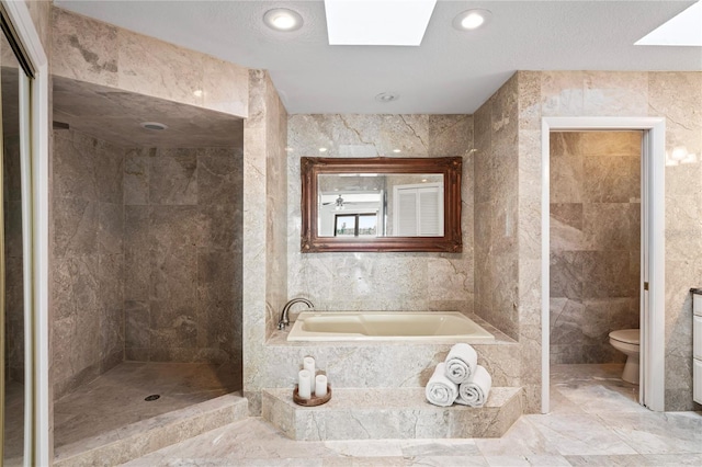 full bath featuring a skylight, tile walls, toilet, a walk in shower, and a bath