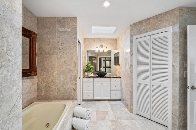 full bathroom featuring a closet, tile walls, a whirlpool tub, and vanity