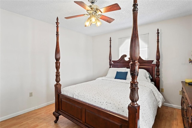 bedroom with a textured ceiling, baseboards, a ceiling fan, and light wood-style floors