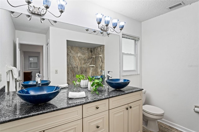 bathroom featuring toilet, visible vents, a sink, and tiled shower