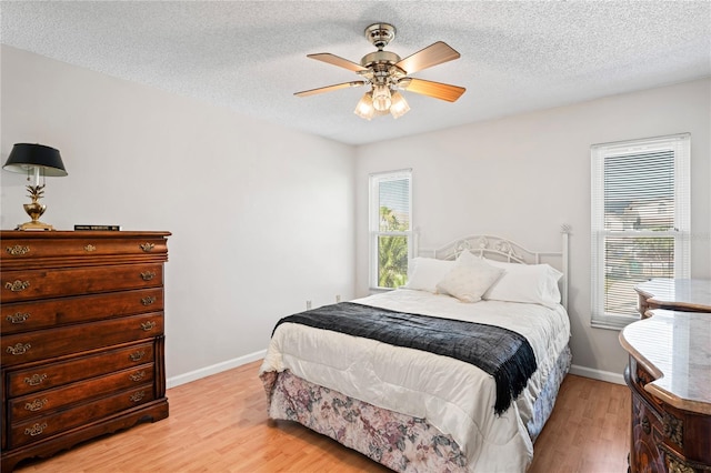 bedroom featuring a textured ceiling, baseboards, and light wood-style floors