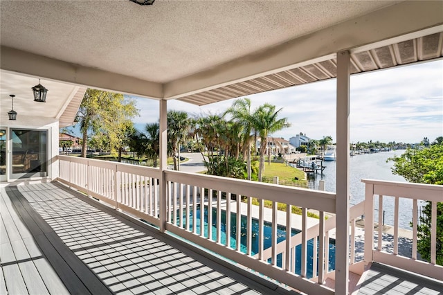 wooden deck featuring a water view and an outdoor pool