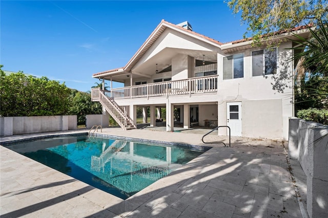 back of property featuring a fenced in pool, stucco siding, a patio area, fence, and stairs