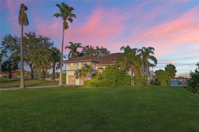 mediterranean / spanish-style home featuring an attached garage, driveway, a front yard, and stucco siding