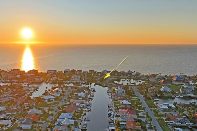 aerial view at dusk featuring a water view and a residential view