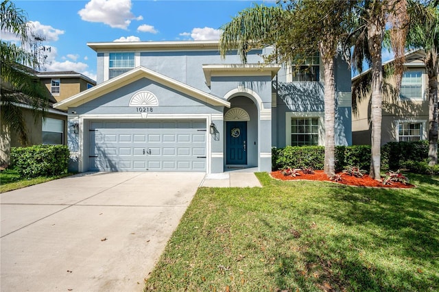 view of front of property with driveway, stucco siding, a garage, and a front yard