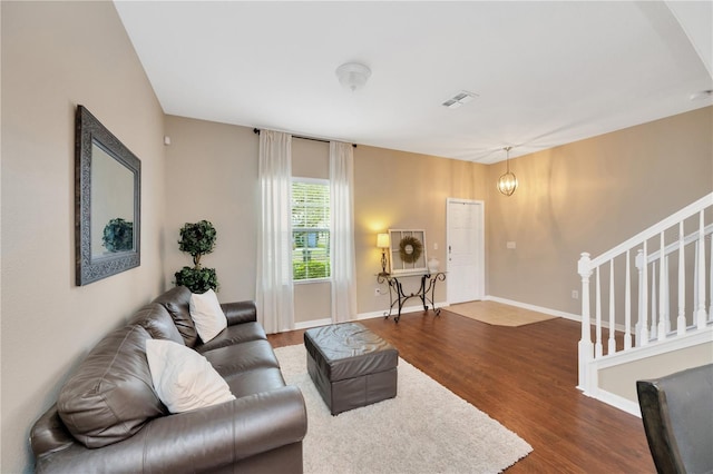 living area featuring dark wood-type flooring, visible vents, stairway, and baseboards