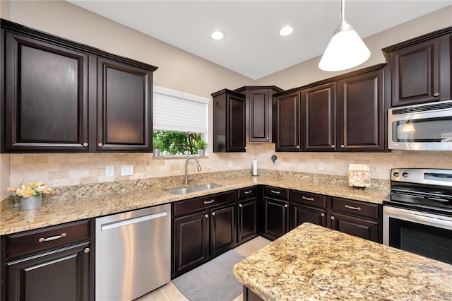 kitchen with dark brown cabinetry, stainless steel appliances, a sink, backsplash, and light stone countertops