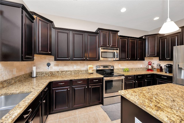 kitchen with light stone countertops, stainless steel appliances, pendant lighting, backsplash, and light tile patterned flooring