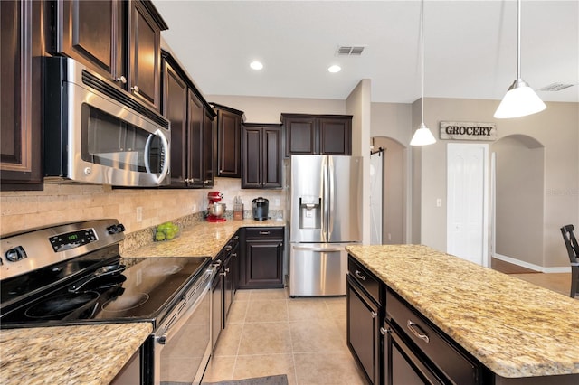 kitchen with arched walkways, dark brown cabinets, appliances with stainless steel finishes, and tasteful backsplash