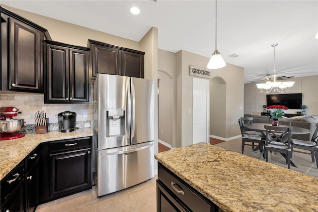 kitchen featuring arched walkways, light tile patterned flooring, open floor plan, stainless steel refrigerator with ice dispenser, and tasteful backsplash