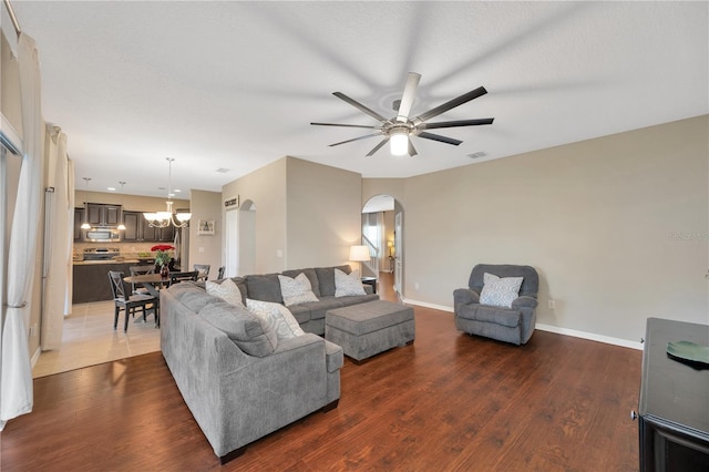 living room with arched walkways, ceiling fan with notable chandelier, wood finished floors, and visible vents