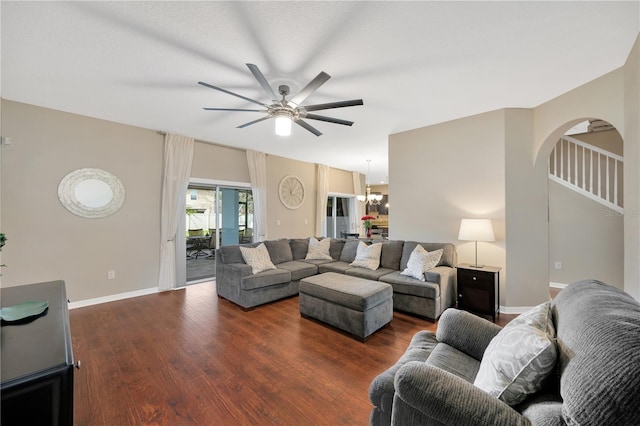 living area featuring ceiling fan with notable chandelier, arched walkways, baseboards, and wood finished floors