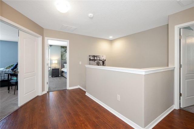 hallway featuring visible vents, baseboards, and wood finished floors