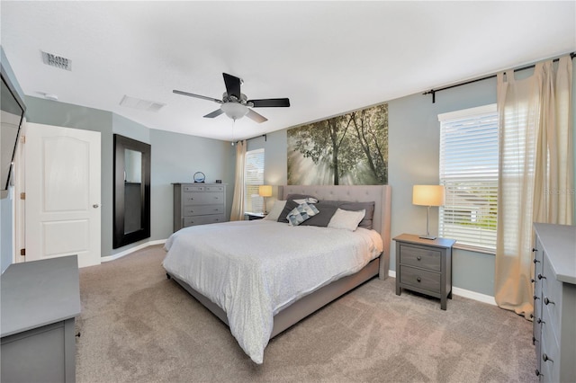 bedroom featuring ceiling fan, visible vents, baseboards, and light colored carpet