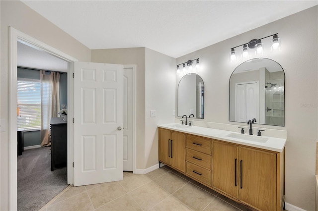 full bath featuring double vanity, tile patterned flooring, baseboards, and a sink