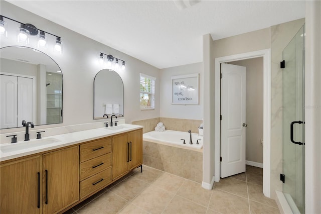 bathroom with a bath, a shower stall, a sink, and tile patterned floors