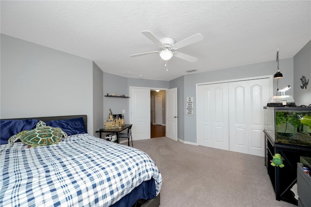 carpeted bedroom with ceiling fan, a textured ceiling, visible vents, and a closet