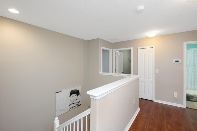 hall with baseboards, wood finished floors, and an upstairs landing