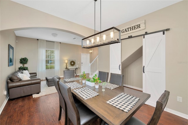 dining space with dark wood-style floors, a barn door, stairs, and baseboards