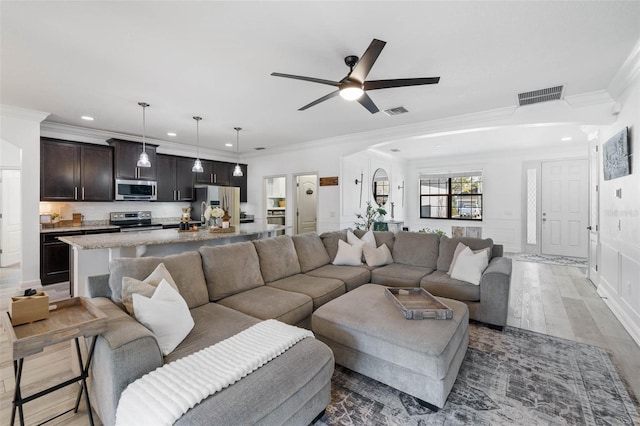 living area featuring crown molding, wood finished floors, visible vents, and ceiling fan