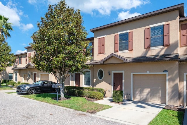 multi unit property featuring a garage, driveway, and stucco siding