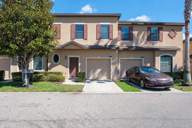 townhome / multi-family property featuring a garage, driveway, and stucco siding