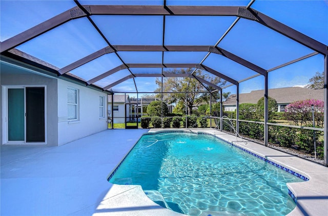 outdoor pool featuring glass enclosure and a patio