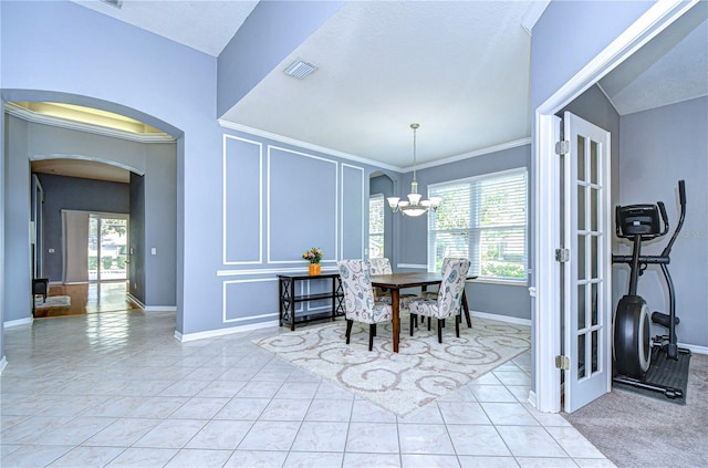 dining area featuring arched walkways, light tile patterned floors, visible vents, a decorative wall, and plenty of natural light