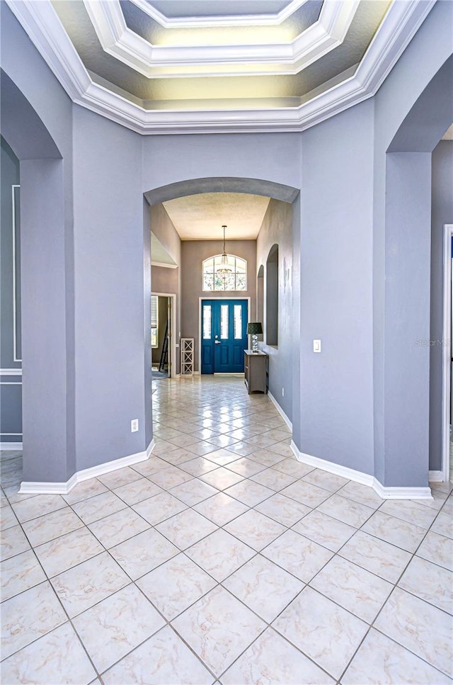 spare room featuring arched walkways, light tile patterned floors, a raised ceiling, and crown molding