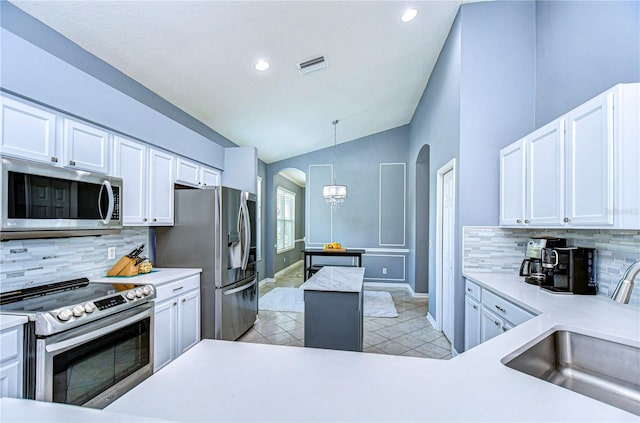 kitchen featuring arched walkways, visible vents, appliances with stainless steel finishes, vaulted ceiling, and a sink