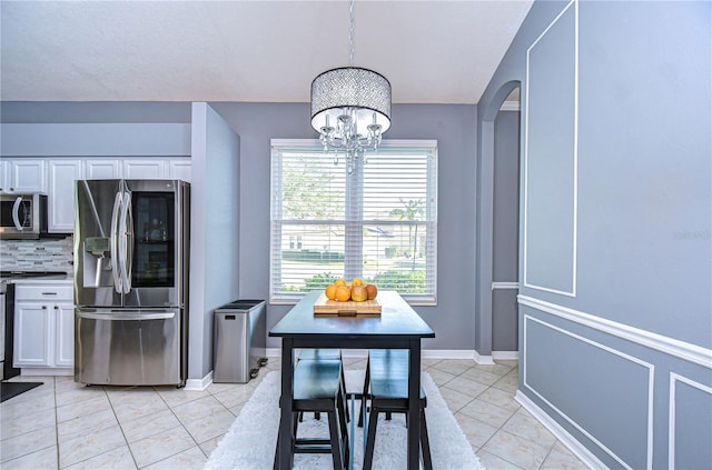 kitchen with arched walkways, light tile patterned flooring, white cabinetry, appliances with stainless steel finishes, and backsplash