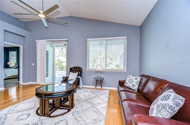 living room featuring vaulted ceiling, plenty of natural light, baseboards, and wood finished floors