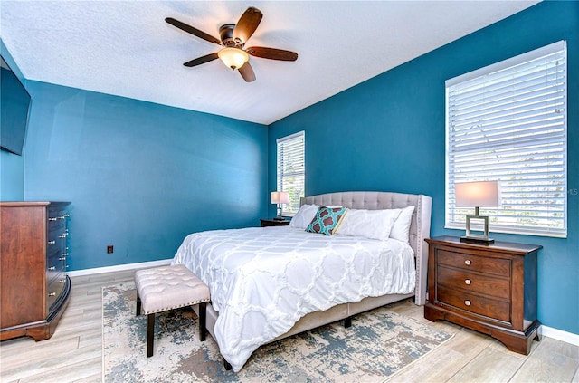 bedroom featuring a ceiling fan, baseboards, and wood finished floors