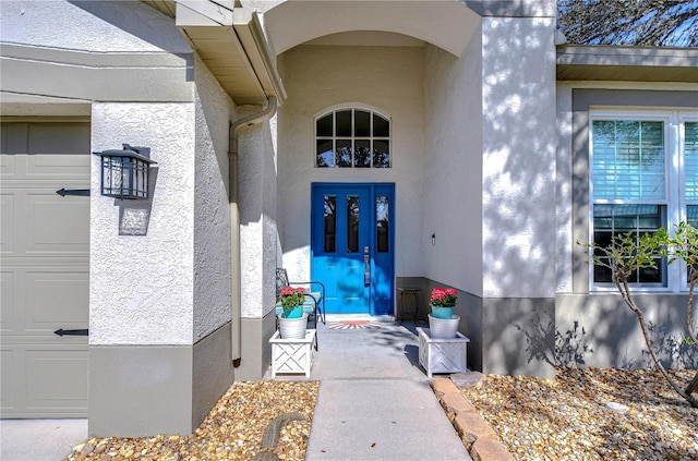 entrance to property featuring an attached garage and stucco siding