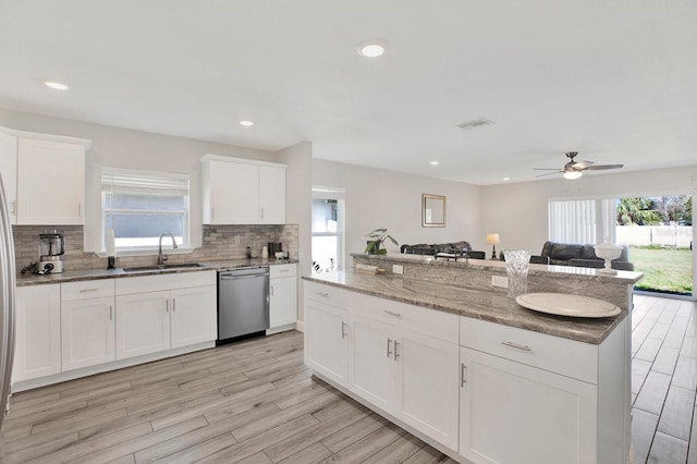 kitchen featuring dishwasher, open floor plan, a sink, and a healthy amount of sunlight