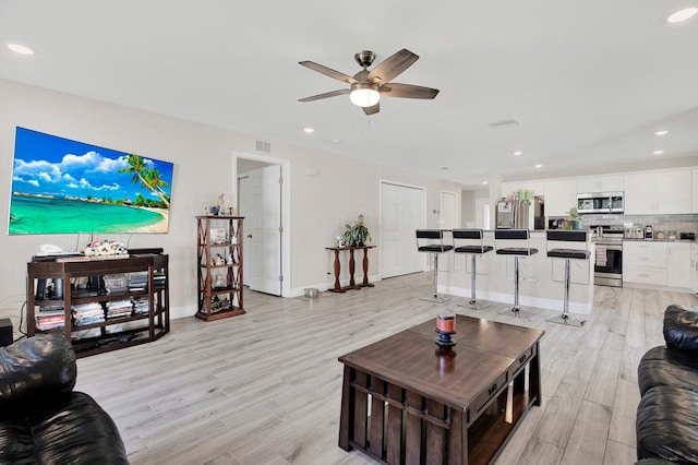 living area with visible vents, recessed lighting, light wood-style flooring, and baseboards