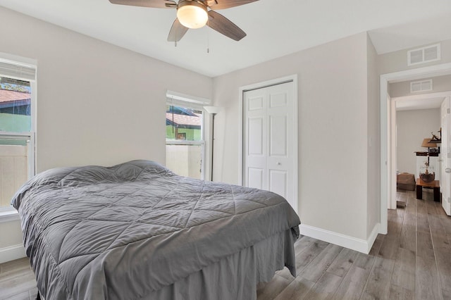 bedroom featuring a closet, visible vents, baseboards, and wood finished floors