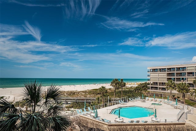 community pool with a beach view, a patio, and a water view