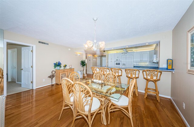 dining area featuring light wood finished floors, visible vents, baseboards, and a notable chandelier