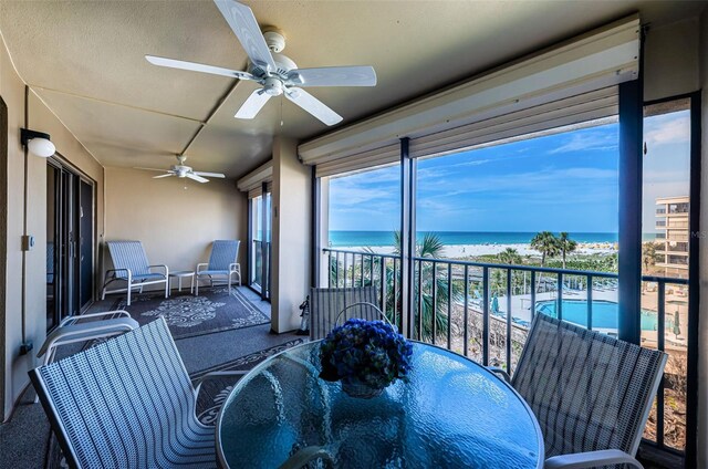 sunroom / solarium featuring a water view and a beach view