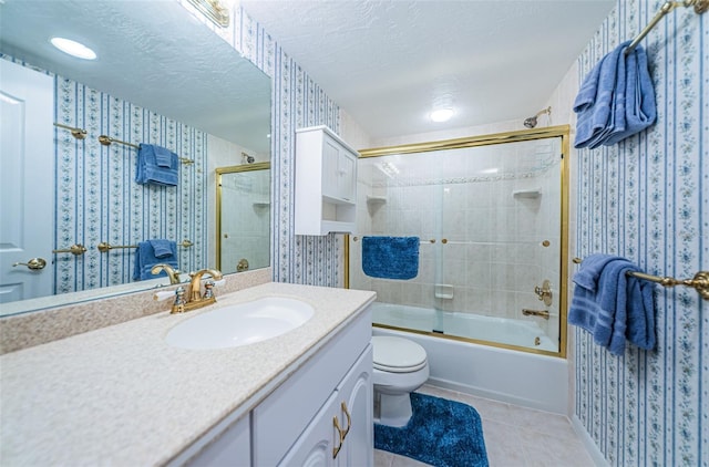 full bath featuring tile patterned flooring, wallpapered walls, bath / shower combo with glass door, vanity, and a textured ceiling