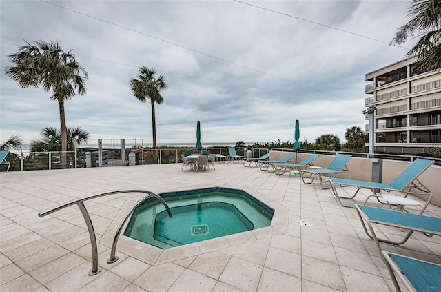 view of pool with a community hot tub, a patio, and fence